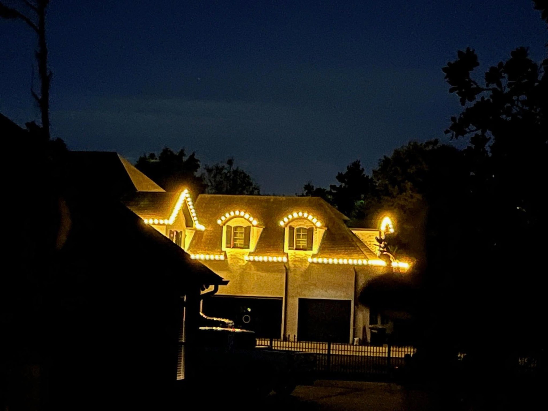 Two-story home outlined in warm white Christmas lights
